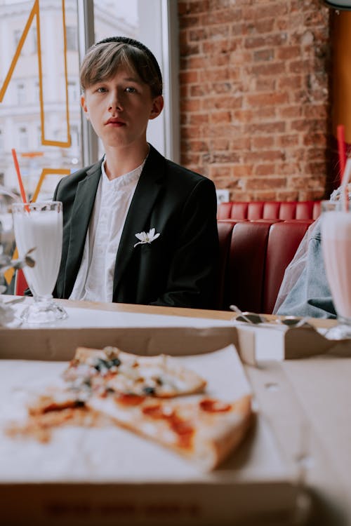 Woman Eating Pizza Sitting by Restaurant Window · Free Stock Photo