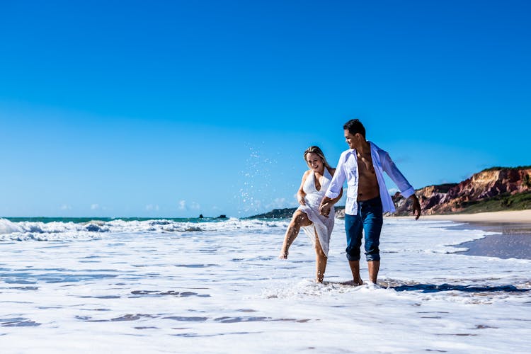 A Couple Holding Hands At The Beach