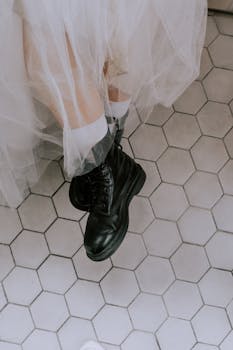 Bride in black boots and wedding dress on hexagonal tile.