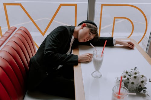 Free Man in Black Outfit Lying Down His Head on the Table  Stock Photo