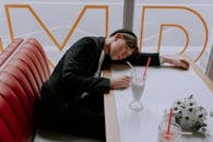 Man in Black Outfit Lying Down His Head on the Table