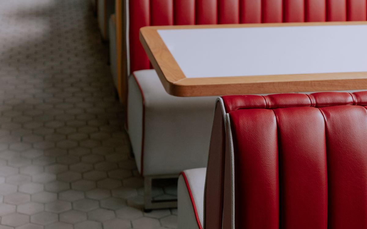 Stylish red leather booth seating in a minimalist cafe setting, perfect for modern dining.
