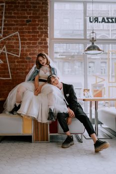 Trendy young couple in wedding outfits relaxing in a vintage café setting.