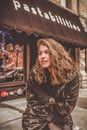 Positive young lady dressed in black warm jacket and gloves basking in cold near signboard of famous restaurant in New York USA