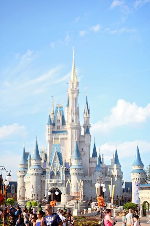 White fairy tale castle with blue roofs in amusement park in Orlando against bright sky on sunny day
