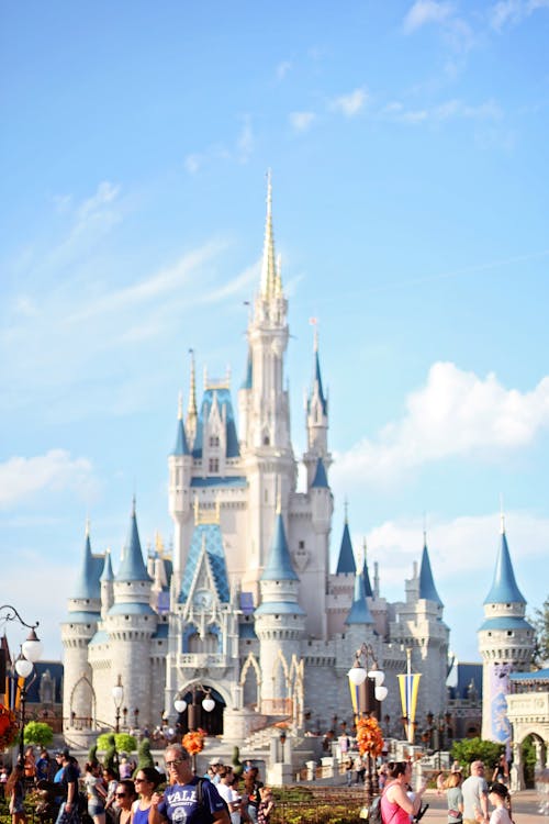 Free White fairy tale castle with blue roofs in amusement park in Orlando against bright sky on sunny day Stock Photo