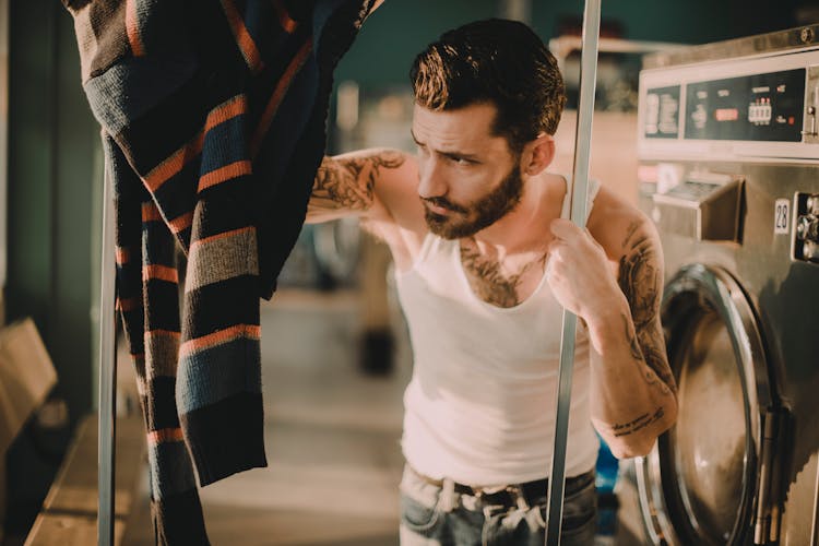 
A Tattooed Bearded Man Holding In A Laundromat