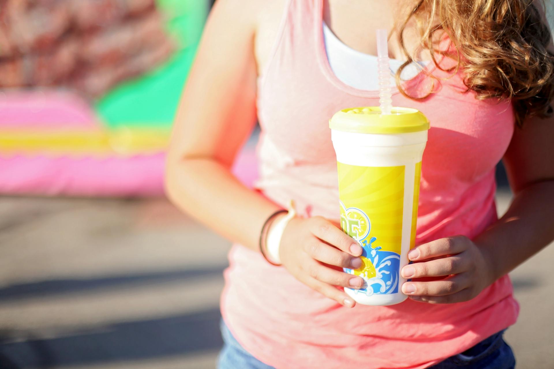 Close-up of a young woman holding a lemonade outdoors during summer.