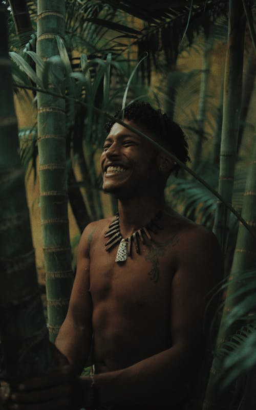 Topless Man Standing Behind Green Bamboo Trees