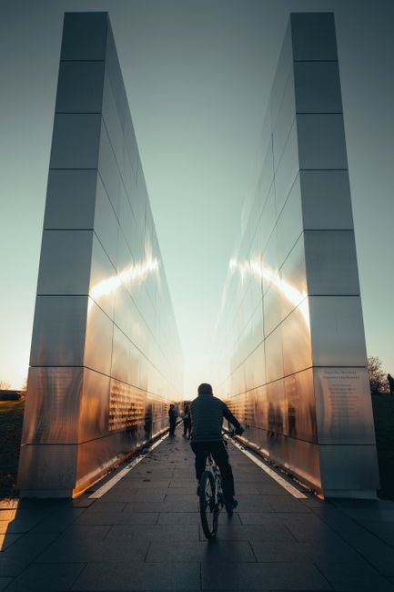 A cyclist rides towards the Empty Sky Memorial in Jersey City at sunset, capturing reflection and remembrance.