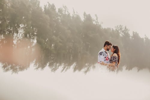 Couple Standing, Hugging and Touching the Tips of Their Noses on a Field 