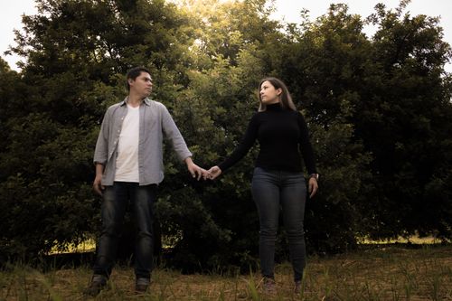Free Couple holding hands in a park, surrounded by nature and trees at daytime. Stock Photo