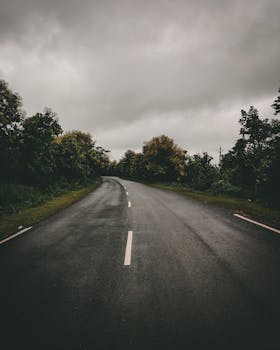 A serene highway in Tinchha, India, with lush greenery and a moody sky, perfect for travel enthusiasts.