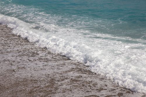 Free Serene ocean waves crashing on a sandy beach with clear turquoise water. Stock Photo