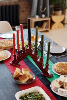 A festive Kwanzaa table set with a kinara and traditional foods, exuding warmth and celebration.