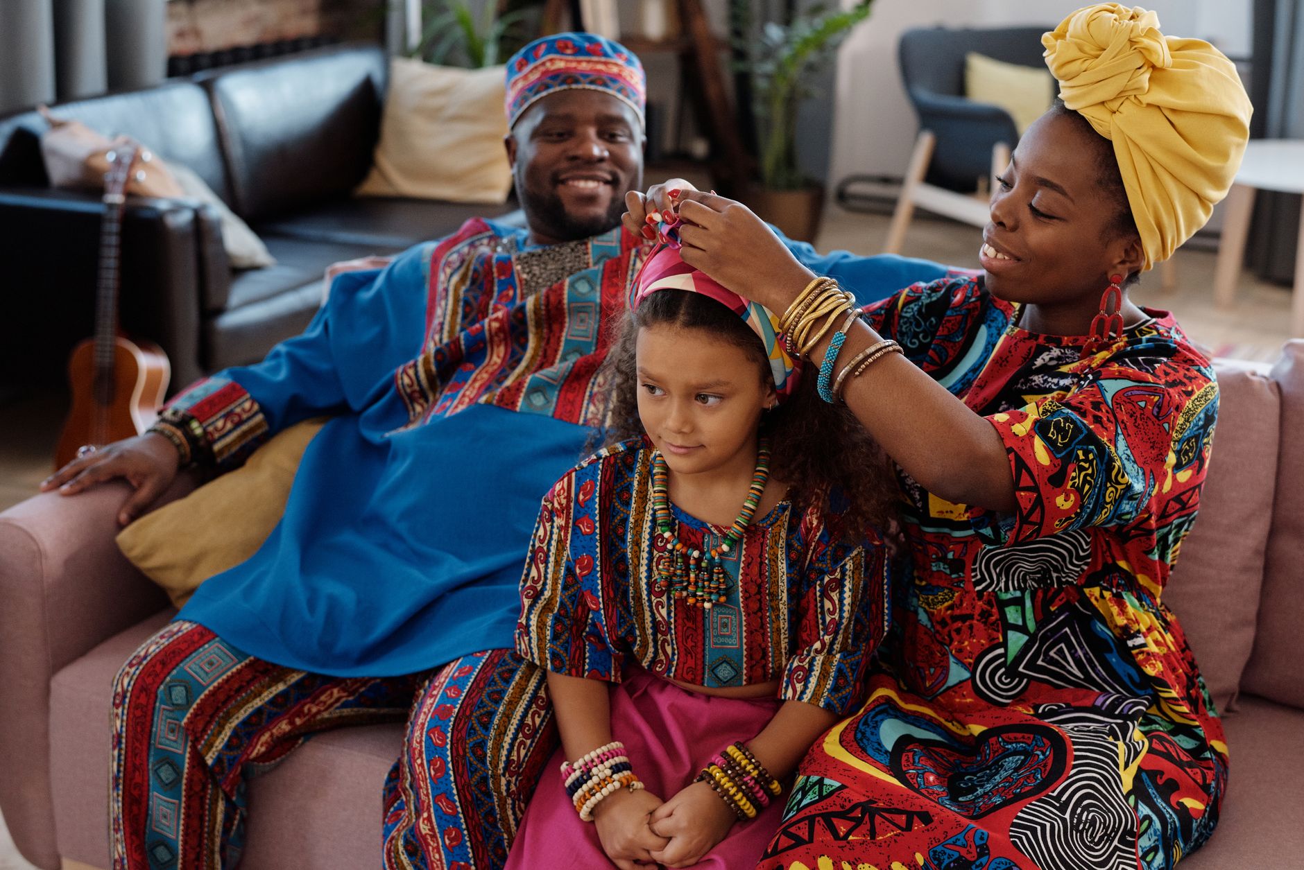 A joyful and loving African family enjoying time together indoors, dressed in vibrant traditional attire.