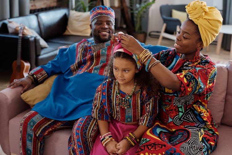 A Family In Traditional Clothing Sitting On A Sofa At Home 