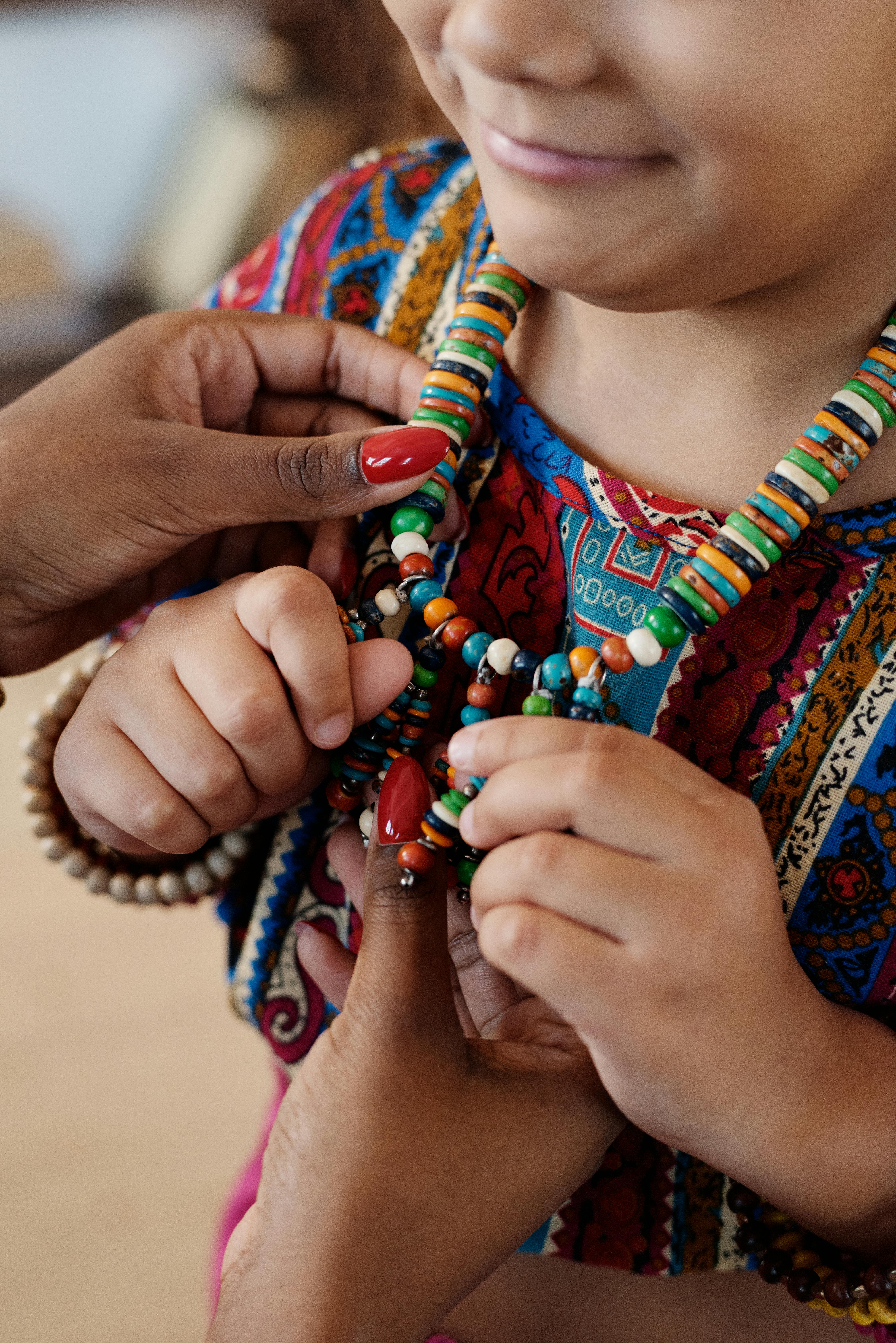 close up photo of child wearing necklace made with beads