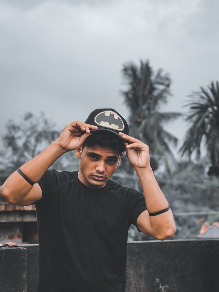 A Man In Black Shirt Holding His Batman Cap