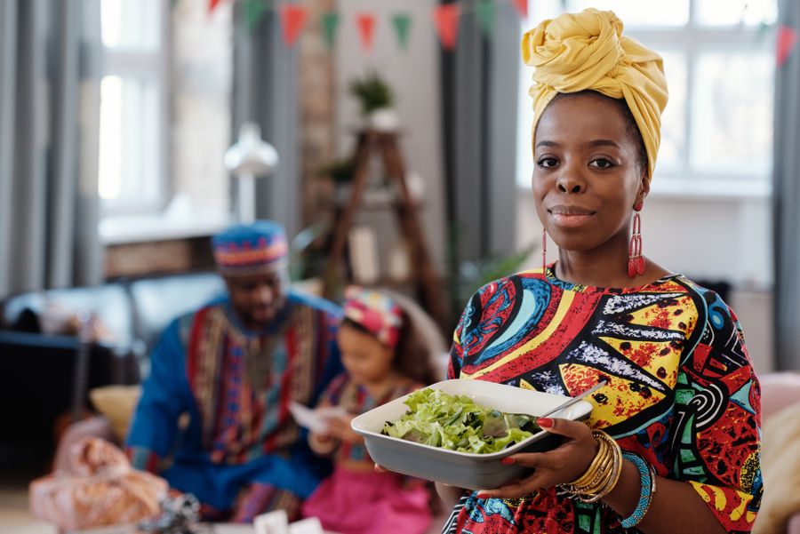 Africans wearing traditional African clothing sharing a meal indoors in America