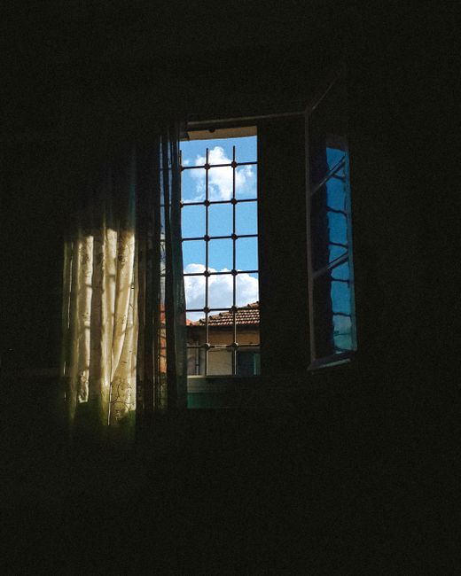 A dreamy view through an open window with security bars, showcasing a vibrant sky.