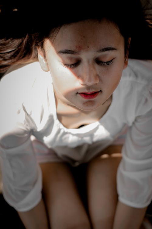 A Woman in White Top with Her Eyes Closed