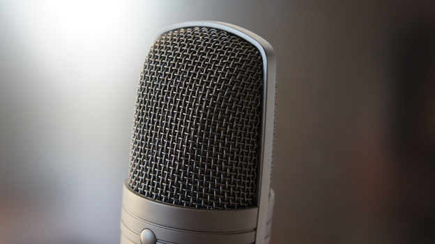 Detailed view of a professional condenser microphone with a blurred backdrop, ideal for audio equipment themes.