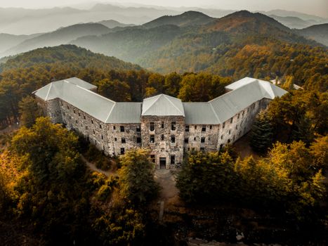 Aerial shot of the historic abandoned Berengaria Hotel surrounded by lush forested mountains in Troodos, Cyprus.