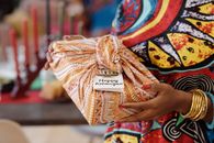 A colorful Kwanzaa celebration featuring a wrapped gift, traditional clothes, and cultural elements.