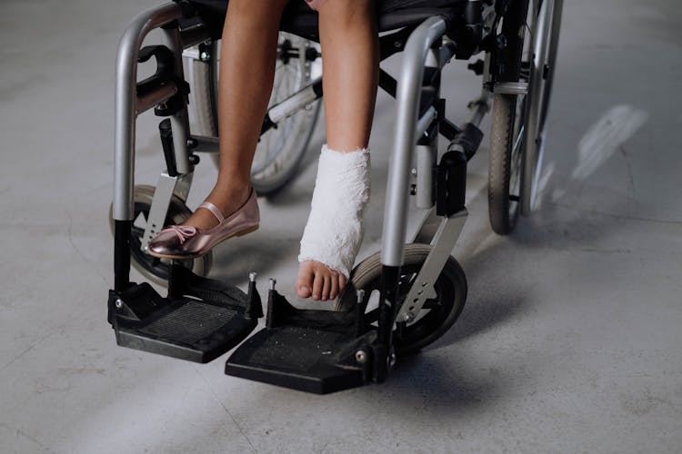 A Girl With Orthopedic Cast Sitting On A Wheelchair