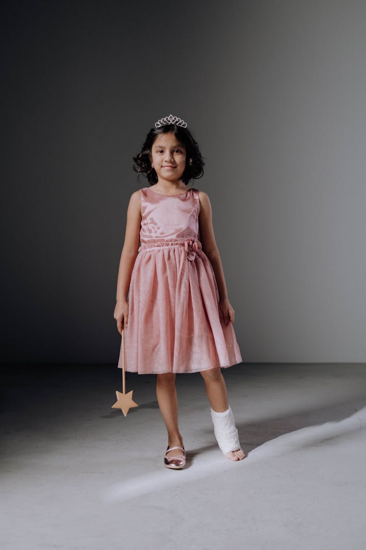 A Girl With Orthopedic Cast Wearing A Pink Dress