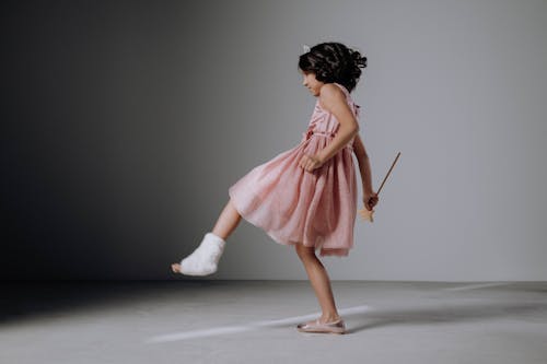 Free A Girl in a Pink Dress Holding a Wand Kicking Stock Photo