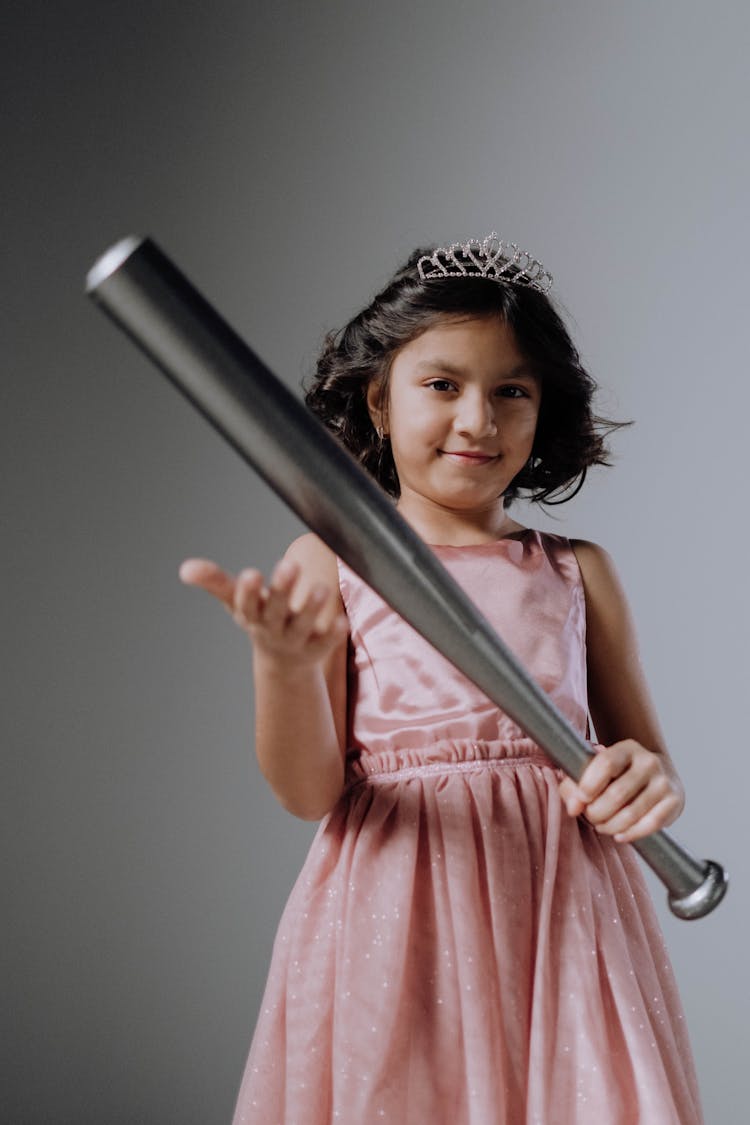 A Girl In Pink Dress Holding A Baseball Bat 