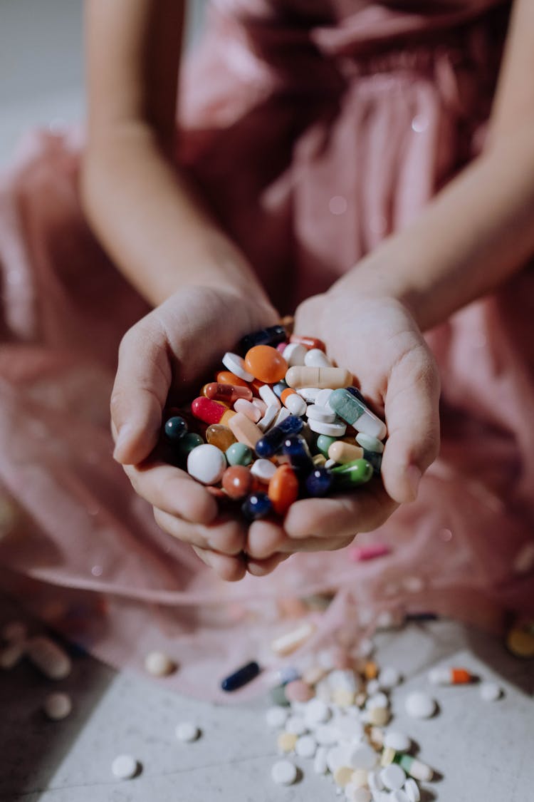 A Handful Of Assorted Medicines On A Child's Hands