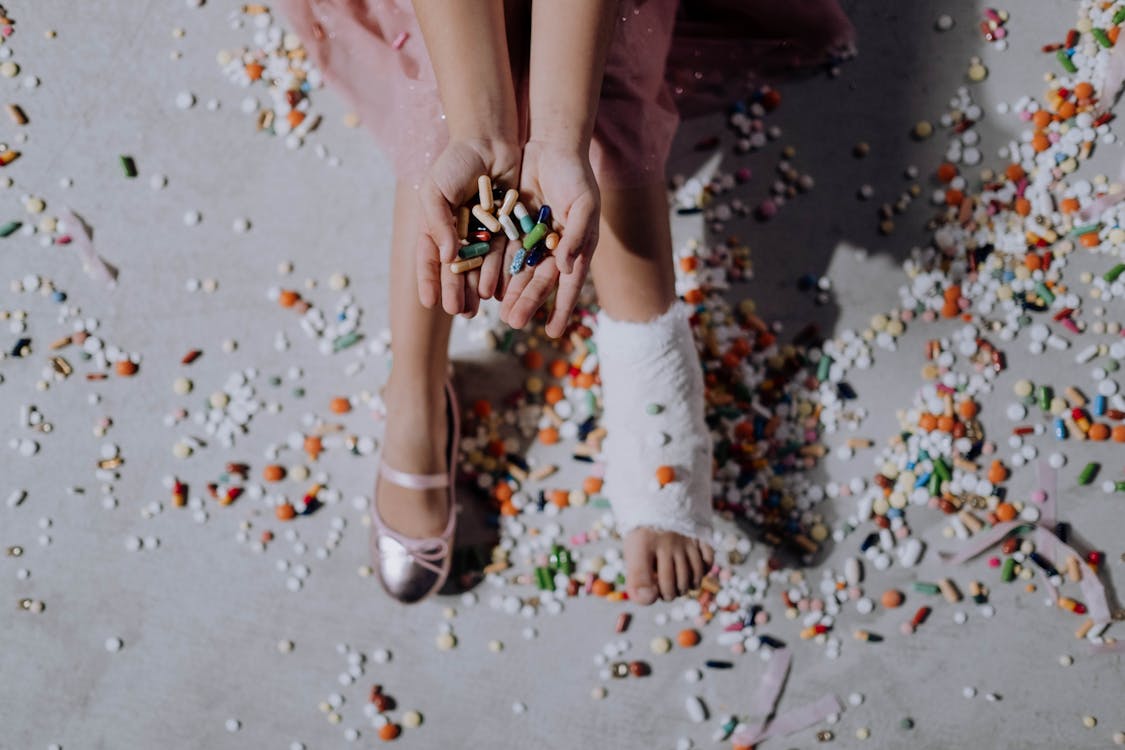 A pair of small hands grasping an assortment of medicines, symbolizing nurturing and health management.