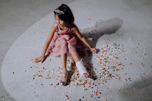Girl in Pink Dress Sitting on Assorted Pills
