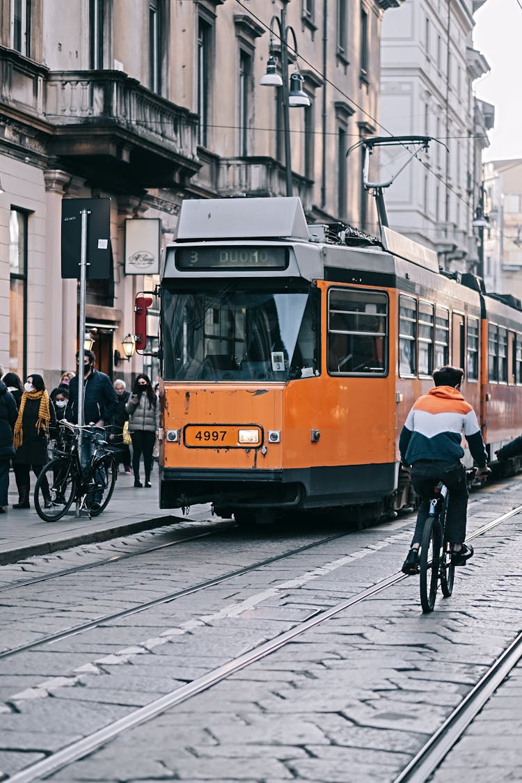 People Walking On Sidewalk Beside A Tram