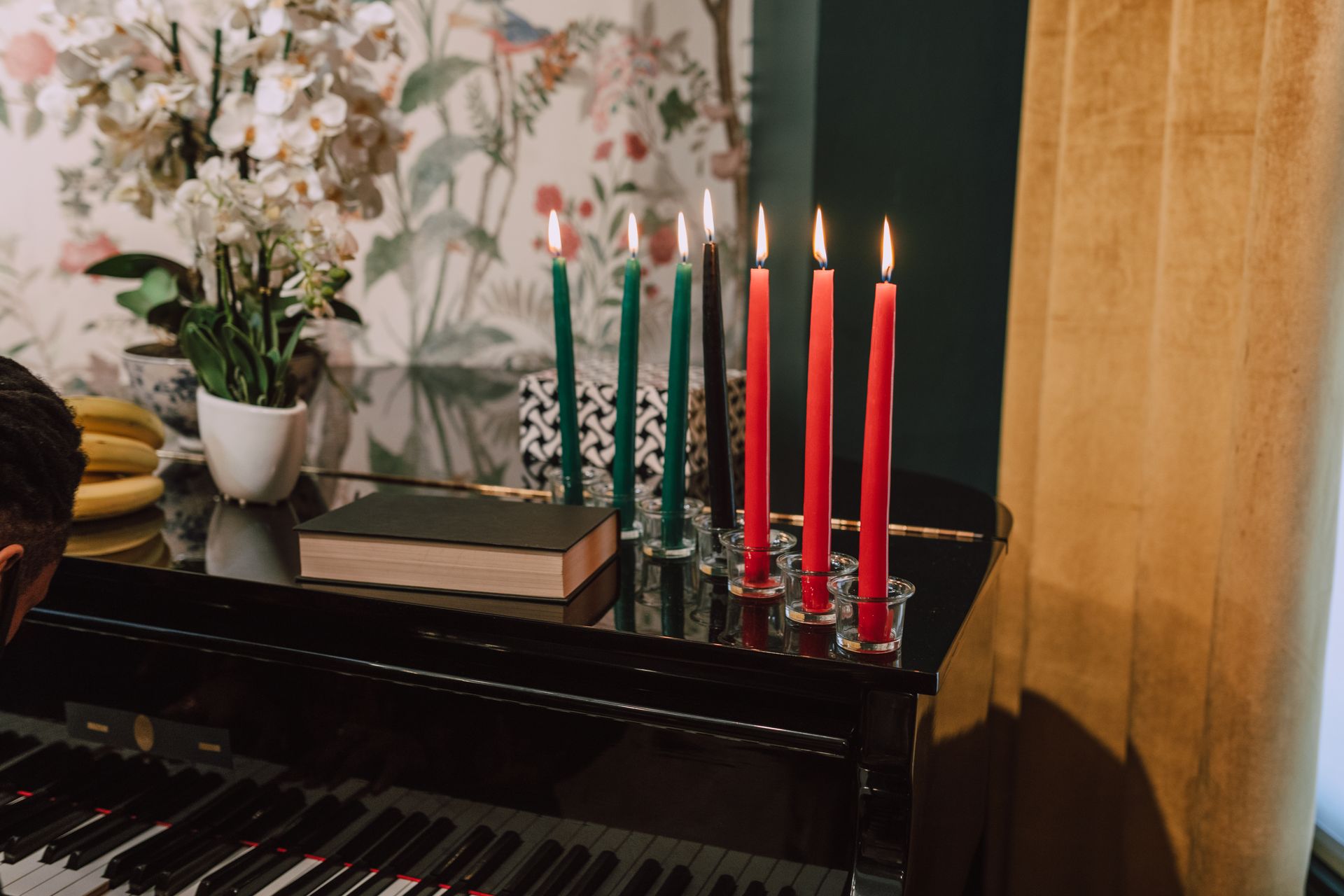 An elegant Kwanzaa scene featuring a kinara with candles, a piano, and decorative flowers indoors.