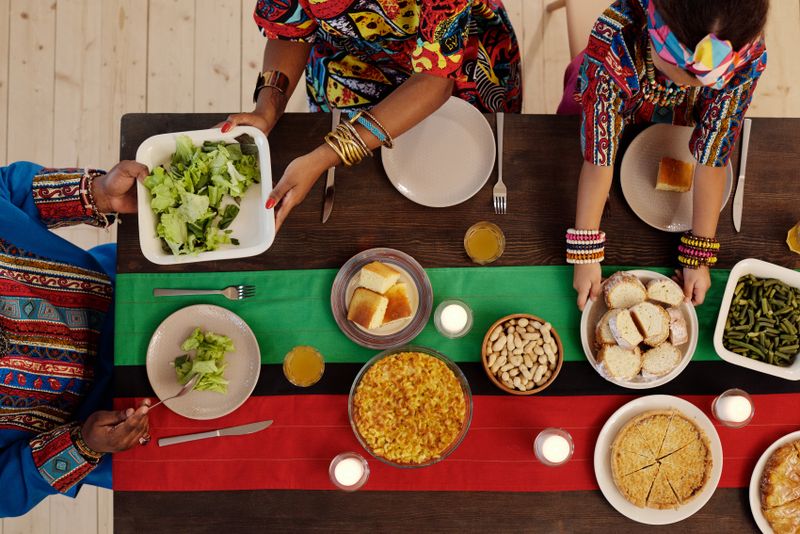Group of people sharing a large communal feast at a table, the heart of a Kenyan Mashujaa Day party