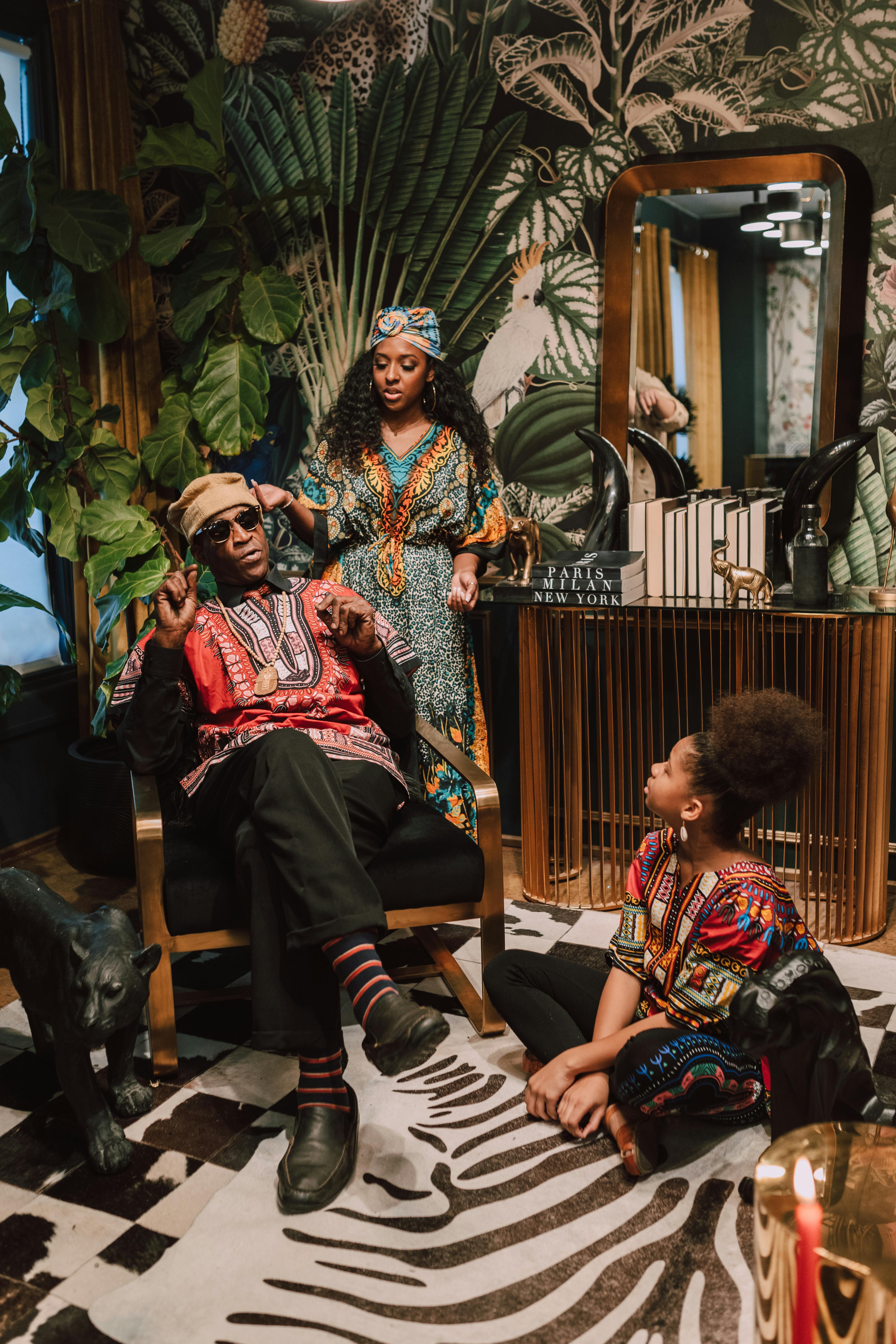 A family joyfully celebrates Kwanzaa in vibrant traditional clothing, surrounded by indoor plants.