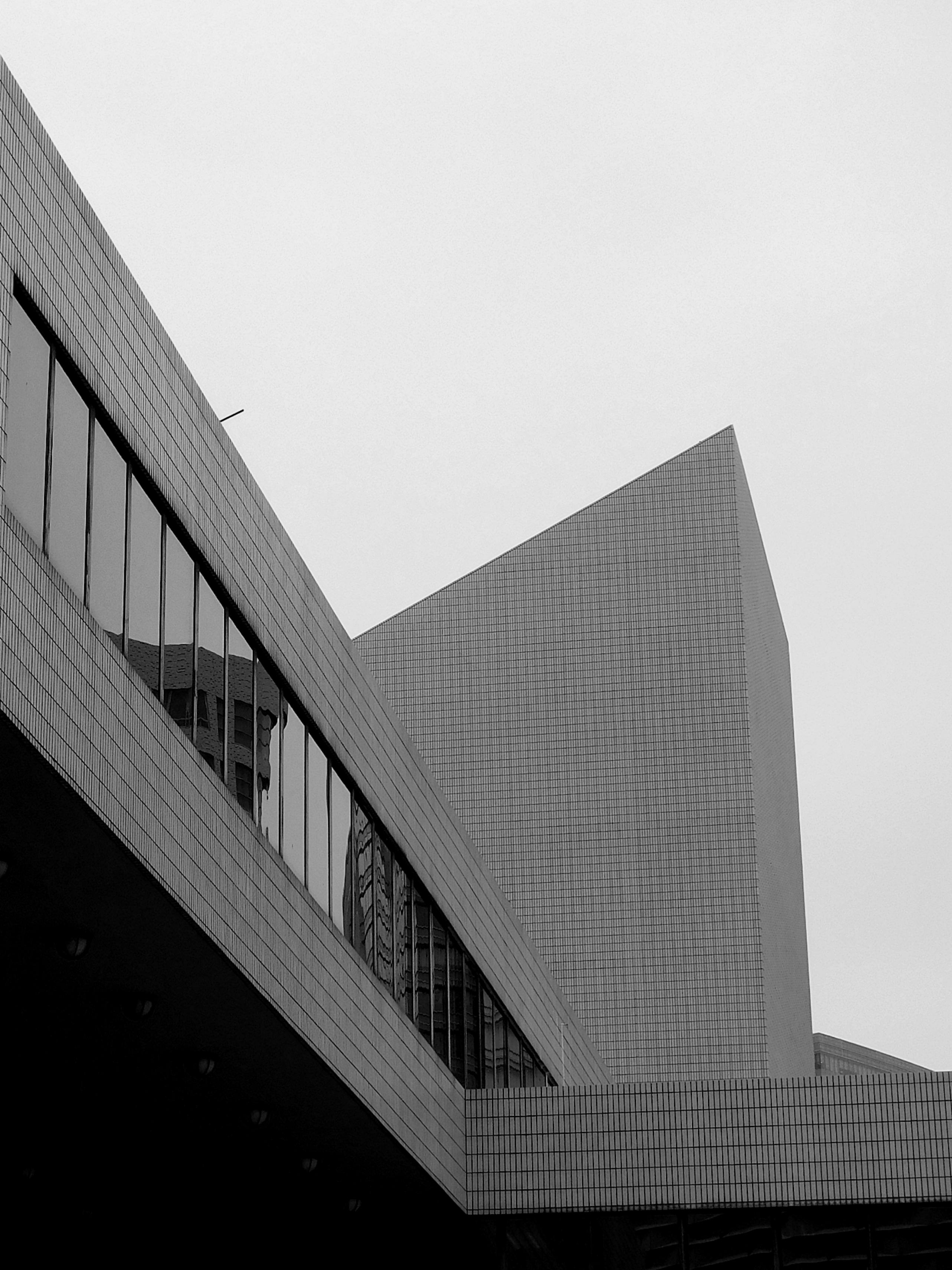 Black and white of contemporary building exterior with glass windows against cloudless sky in city center