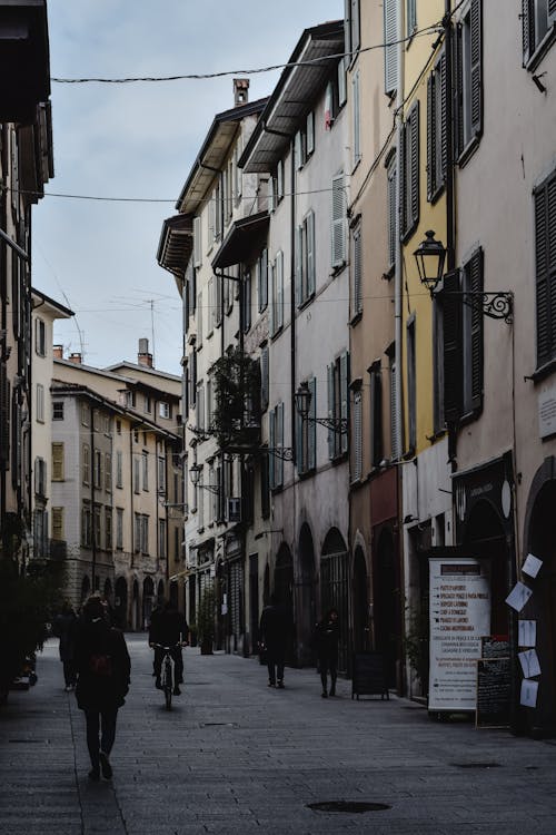 Pedestrians Walking in an Alley between Residential Buildings in City