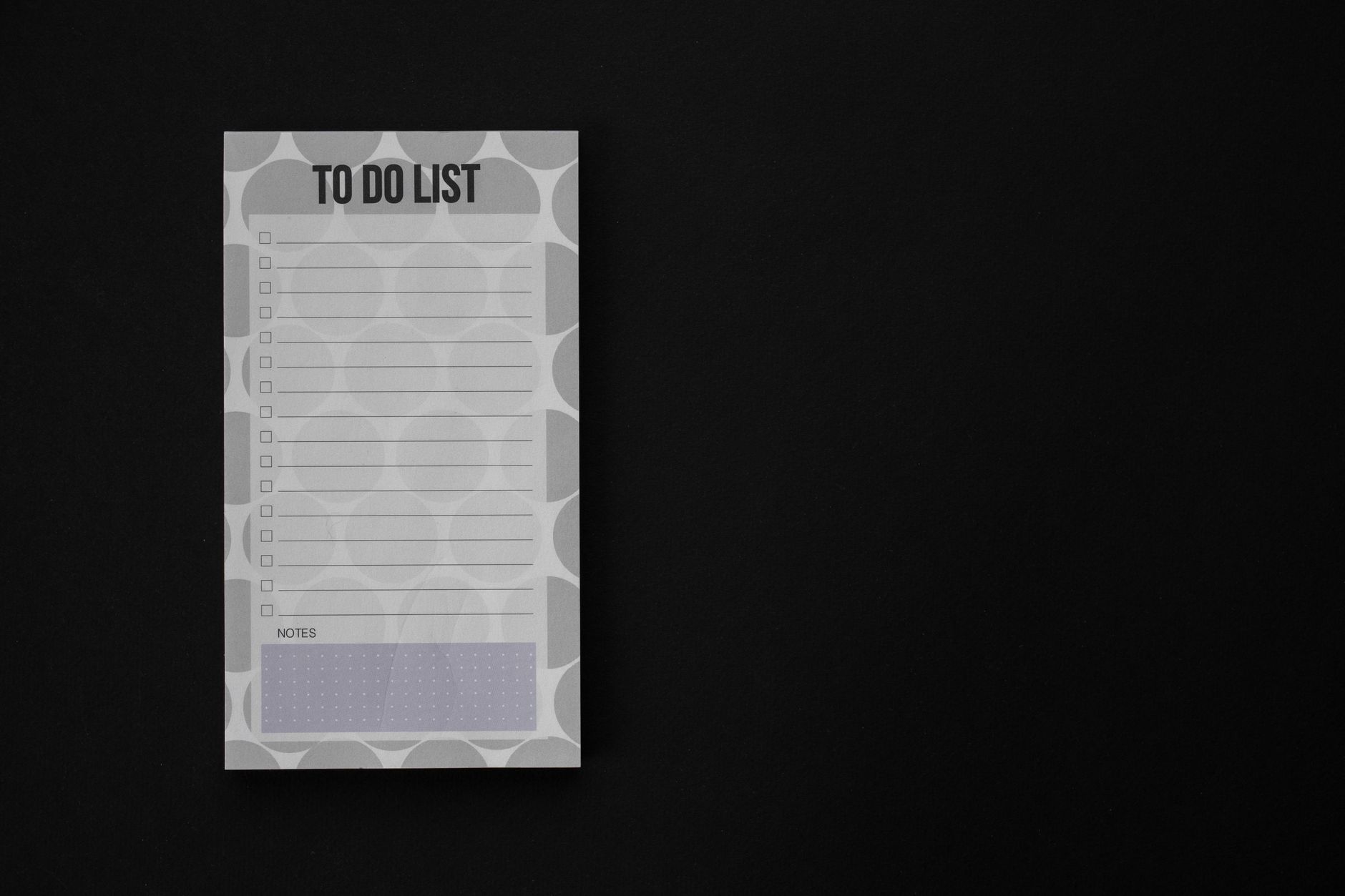 A minimalist to-do list notepad with copy space on a black background, ideal for productivity themes.