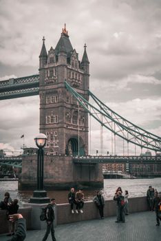View of Tower Bridge with people on the promenade in London, UK.