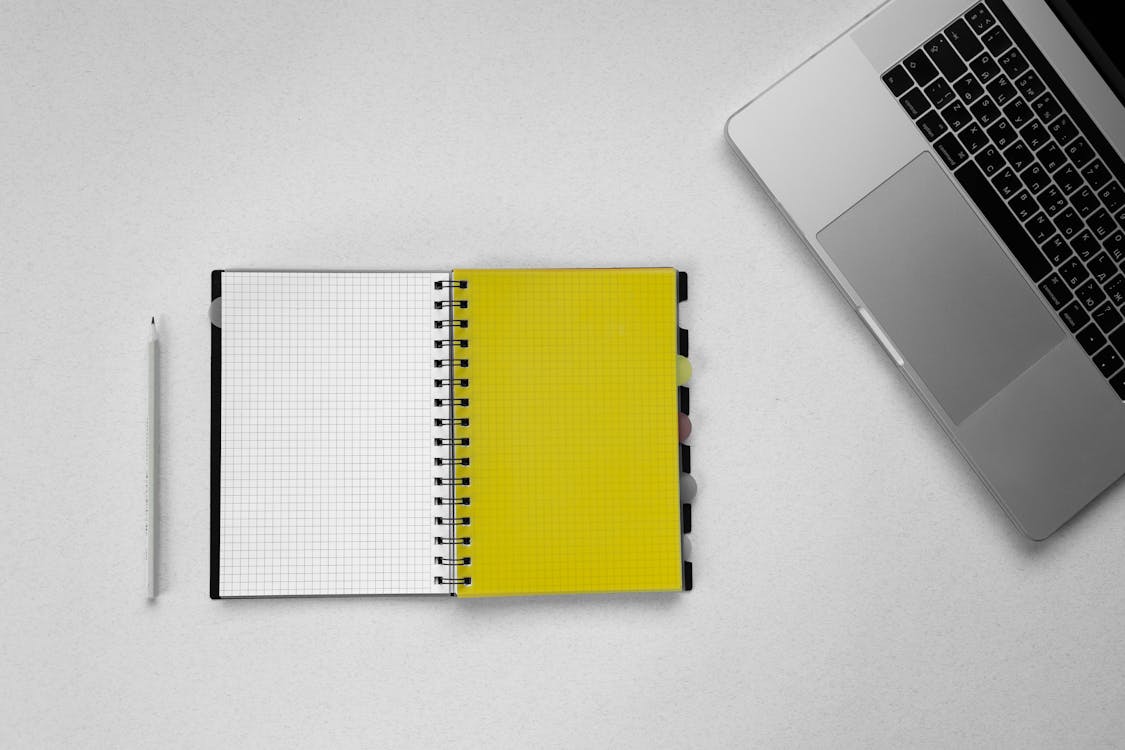Free A Pencil Beside a Grid Notebook Stock Photo