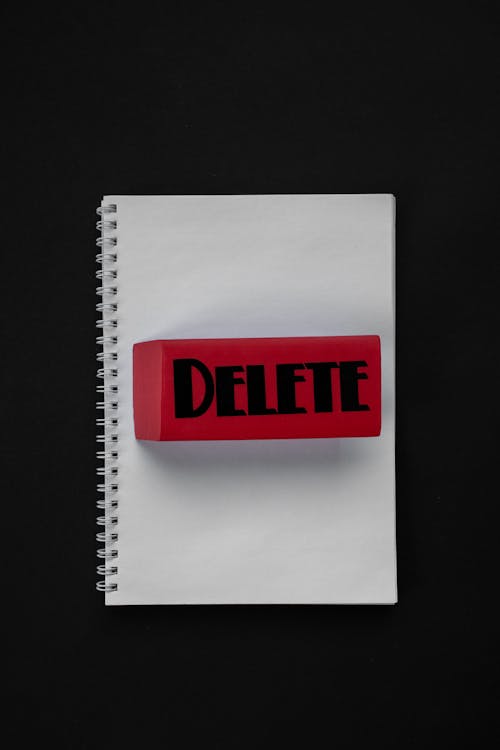 Free Delete Written on a Red Brick on Top of a Notebook Stock Photo