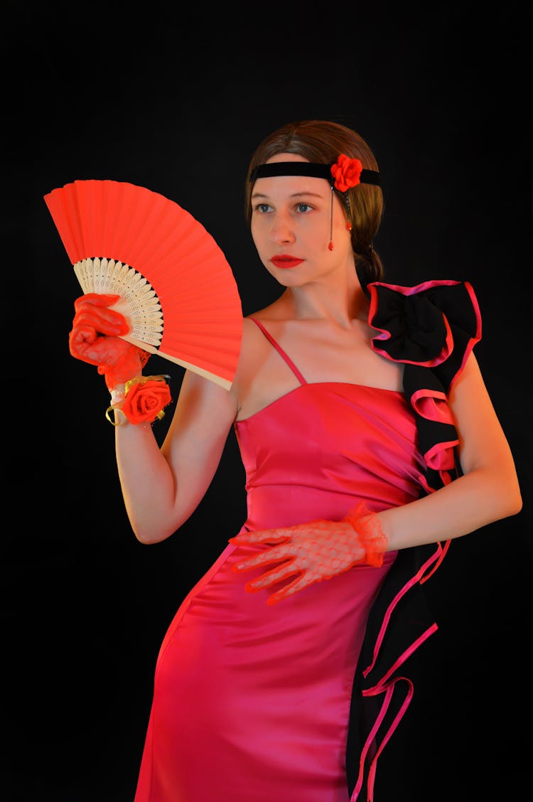 Flamenco Dancer In Bright Dress Standing With Fan And Looking Away