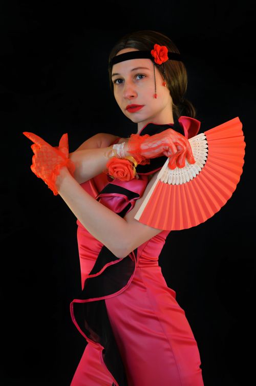 Free Calm female in bright red dress and gloves dancing flamenco with fan against black background in studio Stock Photo