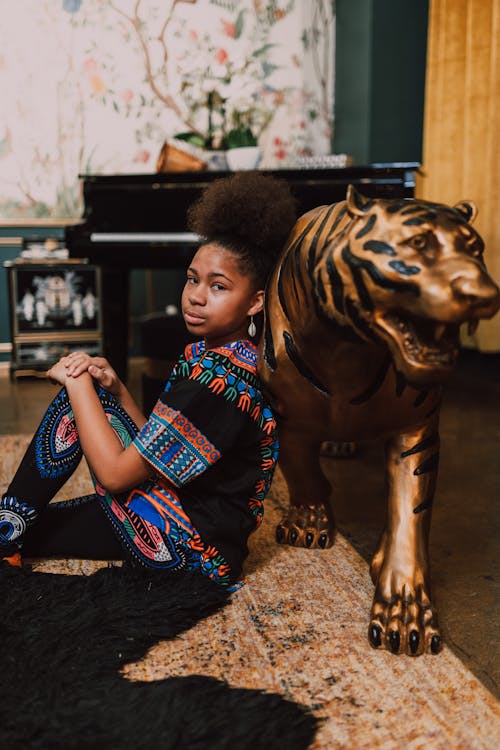 Woman in Blue Kaftan Dress Leaning on Brown Lion Statue