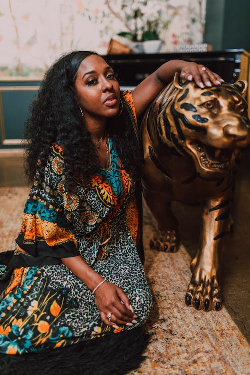 Woman in Black and Brown Dress Holding Gold Lion Statue